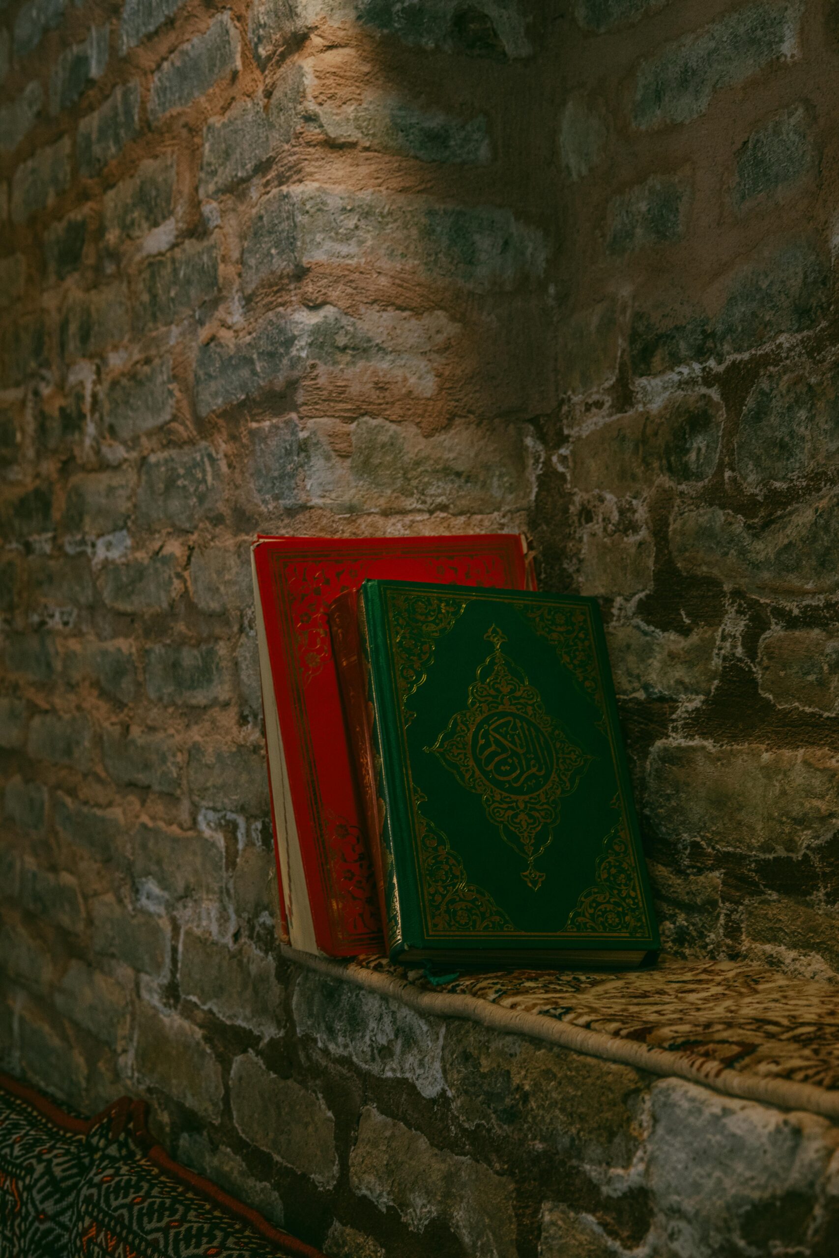 Two ornate books resting against a rustic stone wall, creating a serene atmosphere.