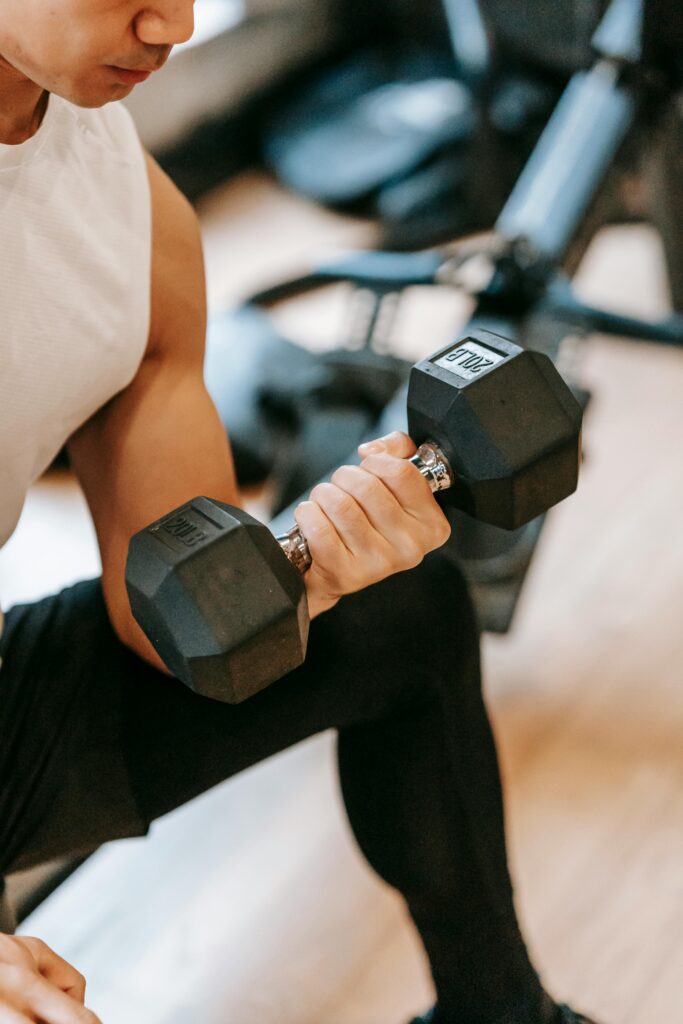 pexels photo 6551411 6551411 Muscular person lifting a dumbbell, highlighting strength and fitness in a gym setting.